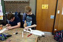 Zwei Jugendliche beim bauen eines Modellflugzeugs.